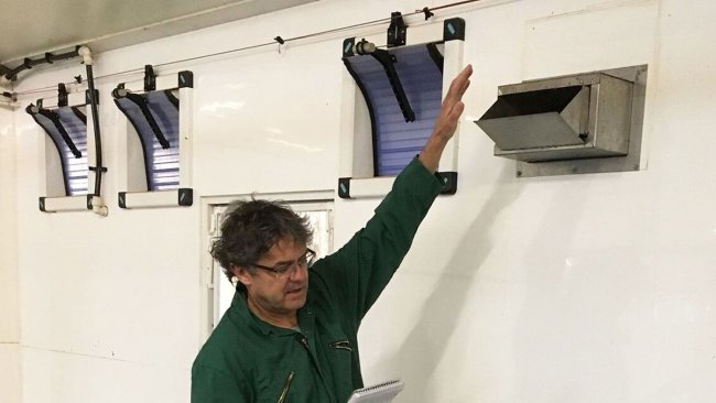 Tim Miller checks a heated air inlet in a weaner-grower house.