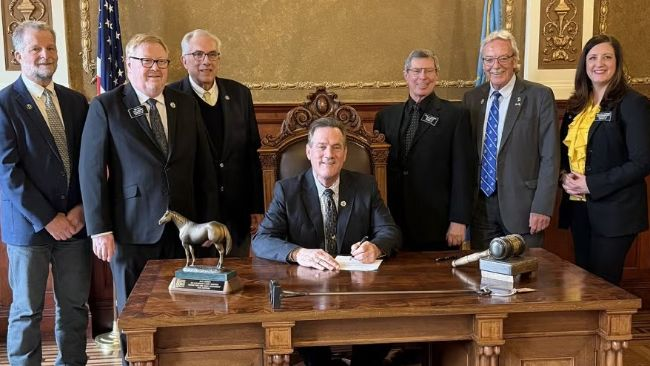 South Dakota State University officials and state lawmakers look on as South Dakota Gov. Larry Rhoden signs a bill Tuesday authorizing the expansion of the SDSU Swine Education and Research Facility.